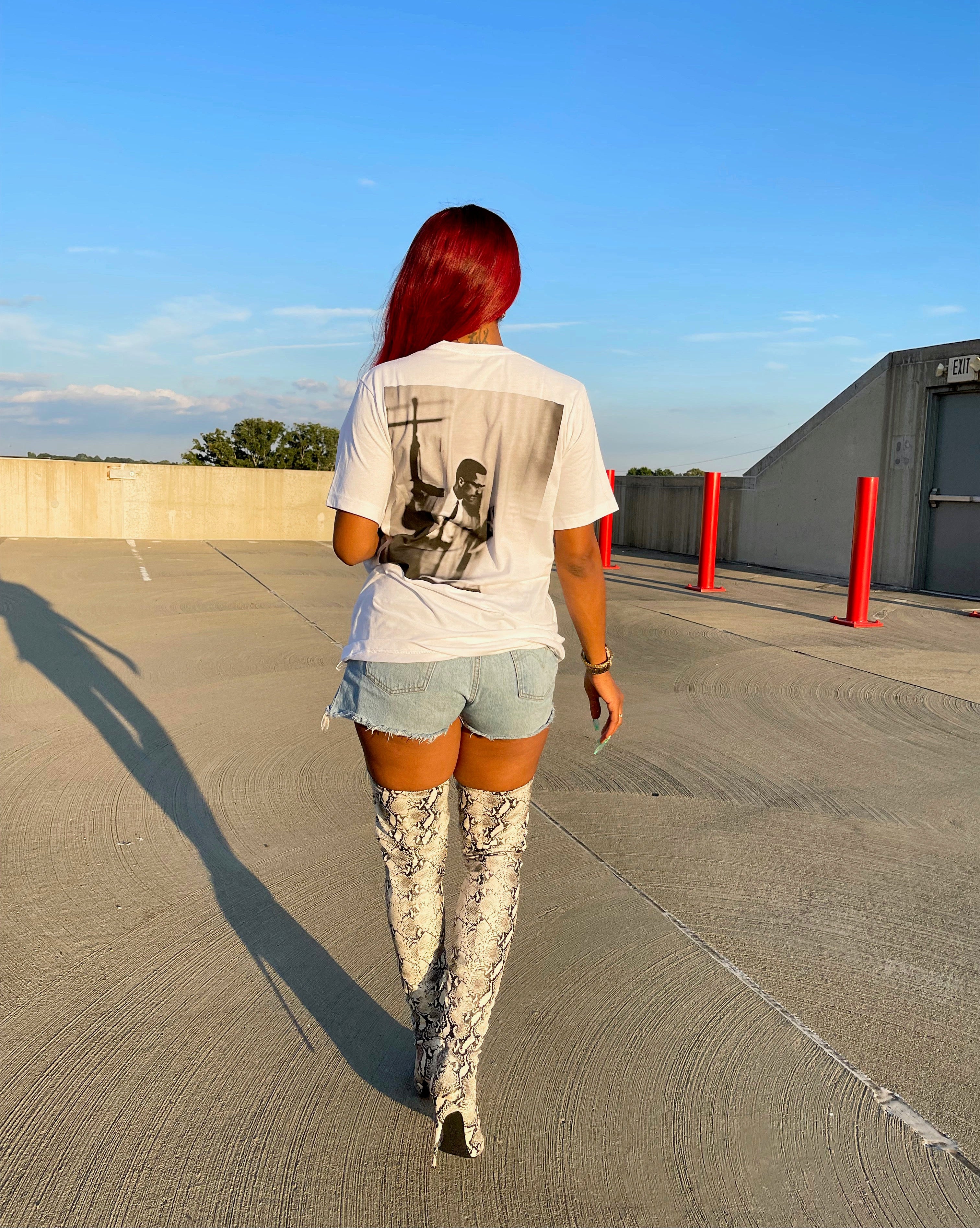 Person walking on a rooftop with a clear blue sky wearing Freedom x Any Means Tee.